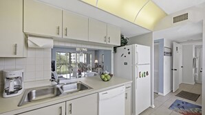 Eine moderne Küche mit weißen Schränken, einer Edelstahl-Spüle, einem Geschirrspüler und einem Kühlschrank.
