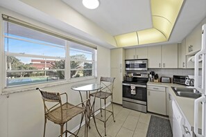 A modern kitchen with a dining area, large windows, and a view of the outdoors.