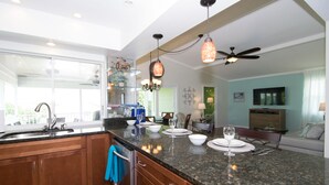 A modern kitchen with granite countertops, stainless steel appliances, and a dining area with a table set for four.