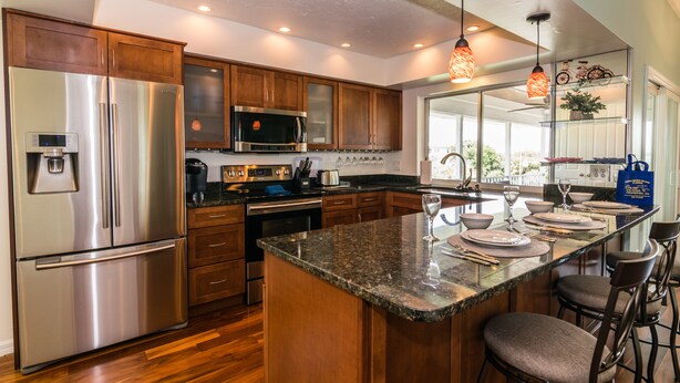 A modern kitchen with stainless steel appliances, wooden cabinets, and a central island with bar seating.