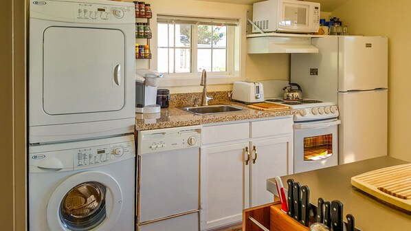 A compact kitchen with a washing machine, microwave, stove, and refrigerator.