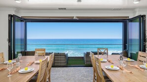 A dining area with a view of the ocean, featuring a wooden table set with plates, glasses, and lemons. - Single Family Beachfront Home, Private Beach P1735-0 (Oceanside)