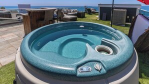 A hot tub with a view of the ocean, surrounded by outdoor furniture and a red umbrella. - Single Family Beachfront Home, Private Beach P1735-0 (Oceanside)