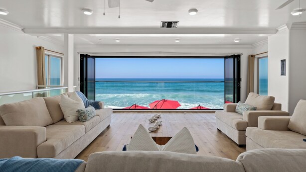 A modern living room with a large glass door leading to a balcony overlooking the ocean. - Single Family Beachfront Home, Private Beach P1735-0 (Oceanside)