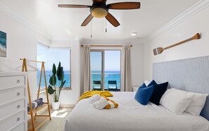 A bedroom with a bed, a ceiling fan, a view of the ocean, a wooden rack, and a potted plant. - Single Family Beachfront Home, Private Beach P1735-0 (Oceanside)