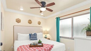 A bedroom with a bed, a ceiling fan, a window with curtains, and wall decorations. - Dreamy Coastal Haven Escape P819-5 (Oceanside)