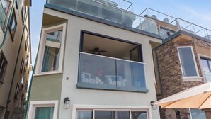 A multi-story building with a balcony, large windows, and a stone facade. - Dreamy Coastal Haven Escape P819-5 (Oceanside)