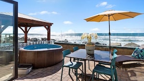 A patio with a hot tub, outdoor seating, and a view of the ocean. - Ultimate Serene Escape P819-6 (Oceanside)