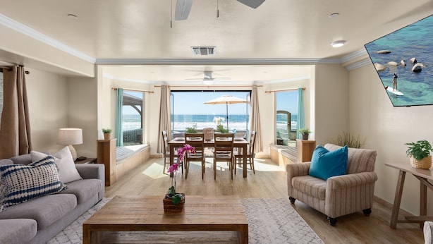 A spacious living room with a view of the ocean, a dining area with a table and chairs, and a cozy seating area with a sofa and armchairs. - Ultimate Serene Escape P819-6 (Oceanside)