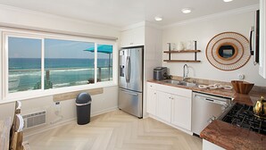 A modern kitchen with a view of the ocean, stainless steel appliances, and a herringbone floor pattern. - Pet Friendly Oceanfront Unit in Oceanside P1315-2 (Oceanside)