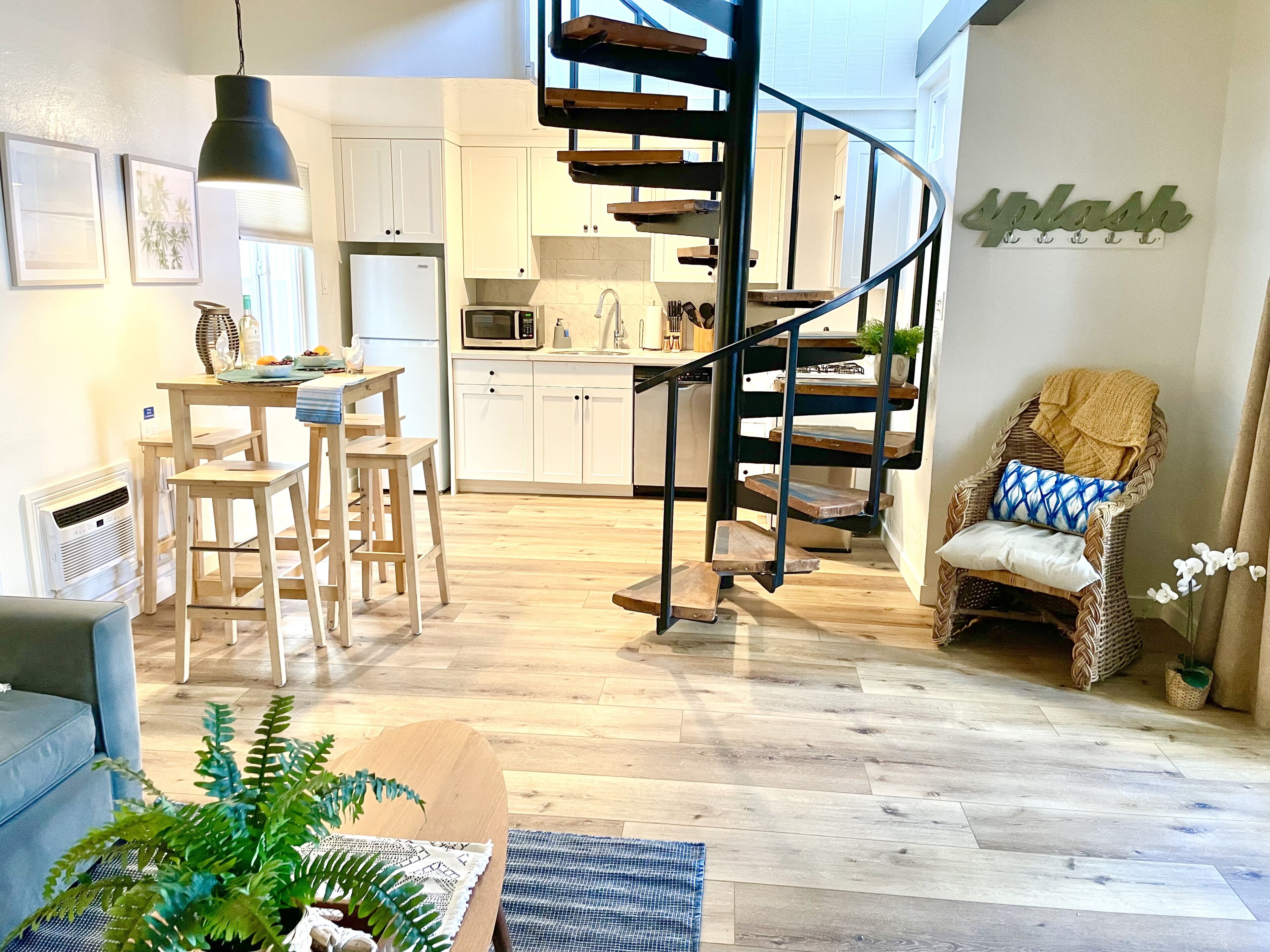 A modern kitchen with white cabinets, a built-in microwave, and a wooden staircase.