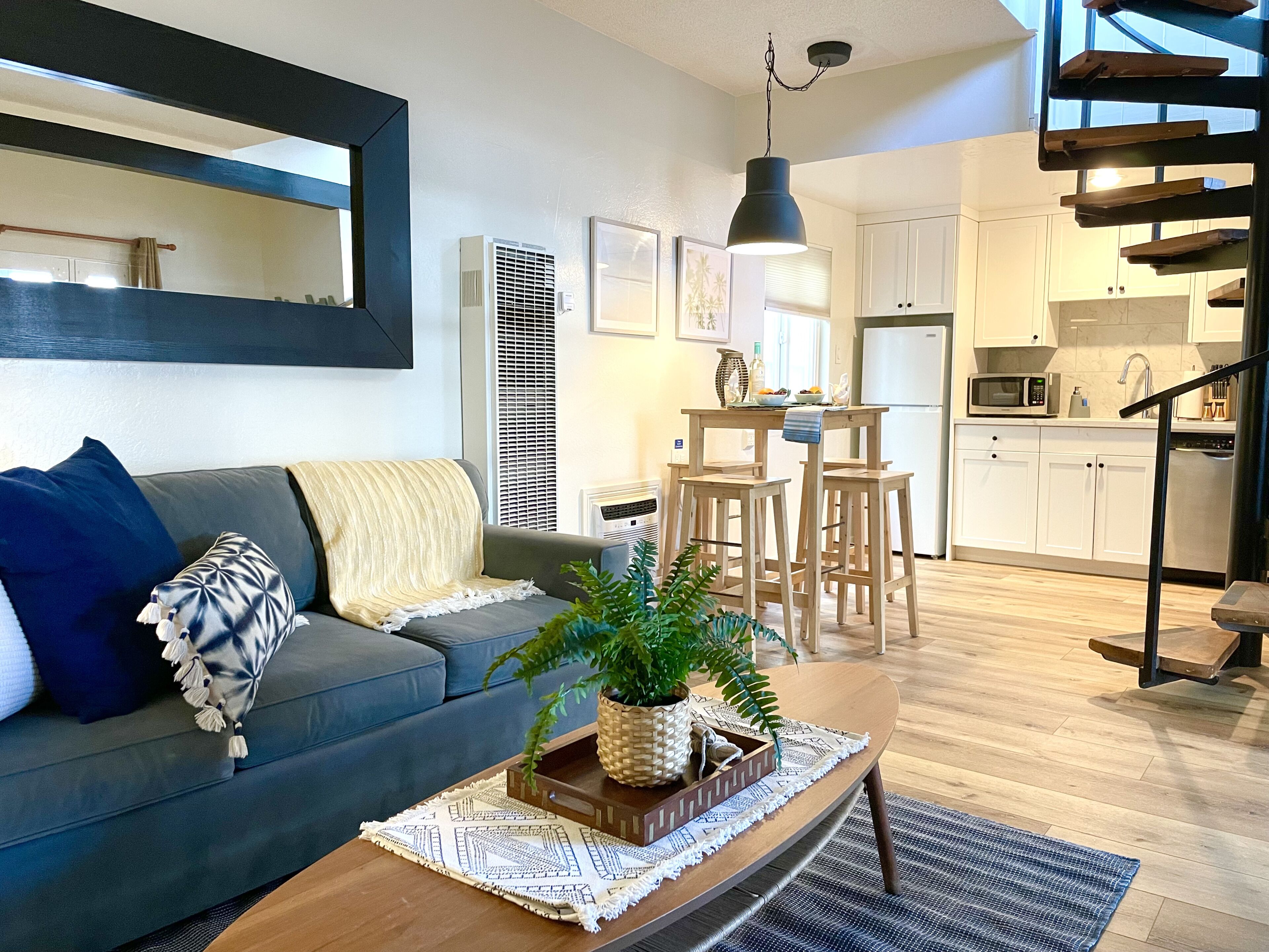 A modern living room with a sofa, coffee table, and a staircase leading to a kitchen.