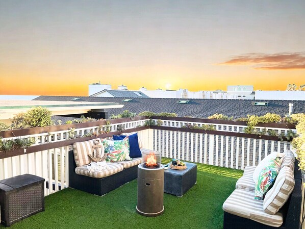 A rooftop patio with a fire pit, outdoor furniture, and a view of the sunset. - Quaint Beachside Escape P1615-4 (Oceanside)