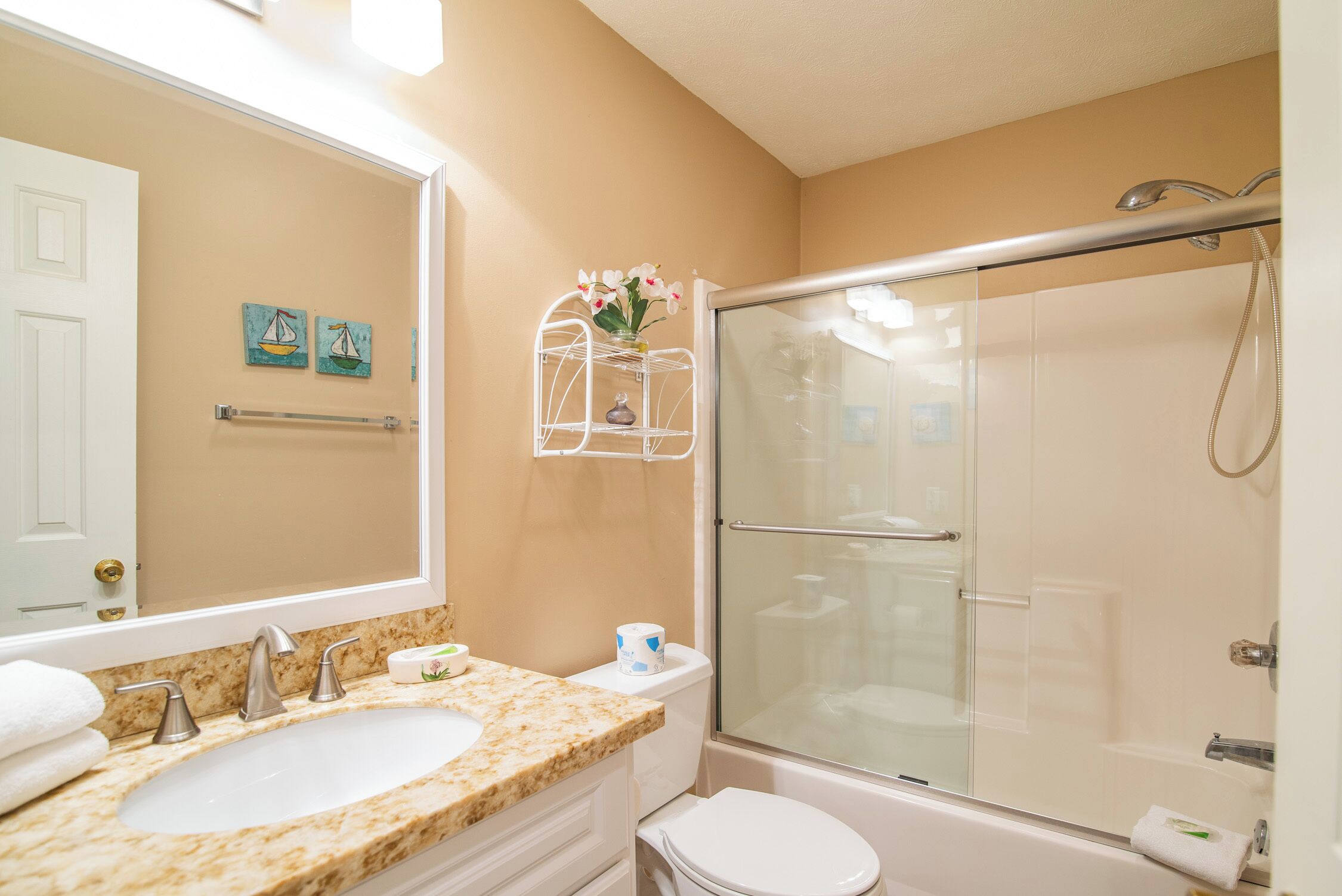 A bathroom with a sink, toilet, and glass-enclosed shower.