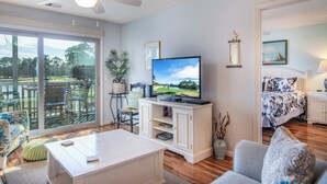 A living room with a television, a sofa, a coffee table, and a dining area with a table and chairs.