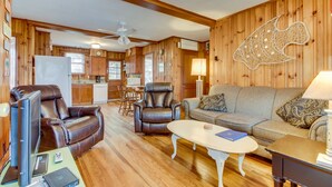 A cozy living room with leather chairs, a sofa, and a coffee table. A television is on a stand, and a remote control is on the floor. - Tip Ellen on Pawleys Island - Second Row, Pet Friendly (Pawleys Island)