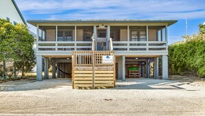 A two-story building with a covered entrance and a wooden gate labeled "Tidelife" and phone number. - Tip Ellen on Pawleys Island - Second Row, Pet Friendly (Pawleys Island)