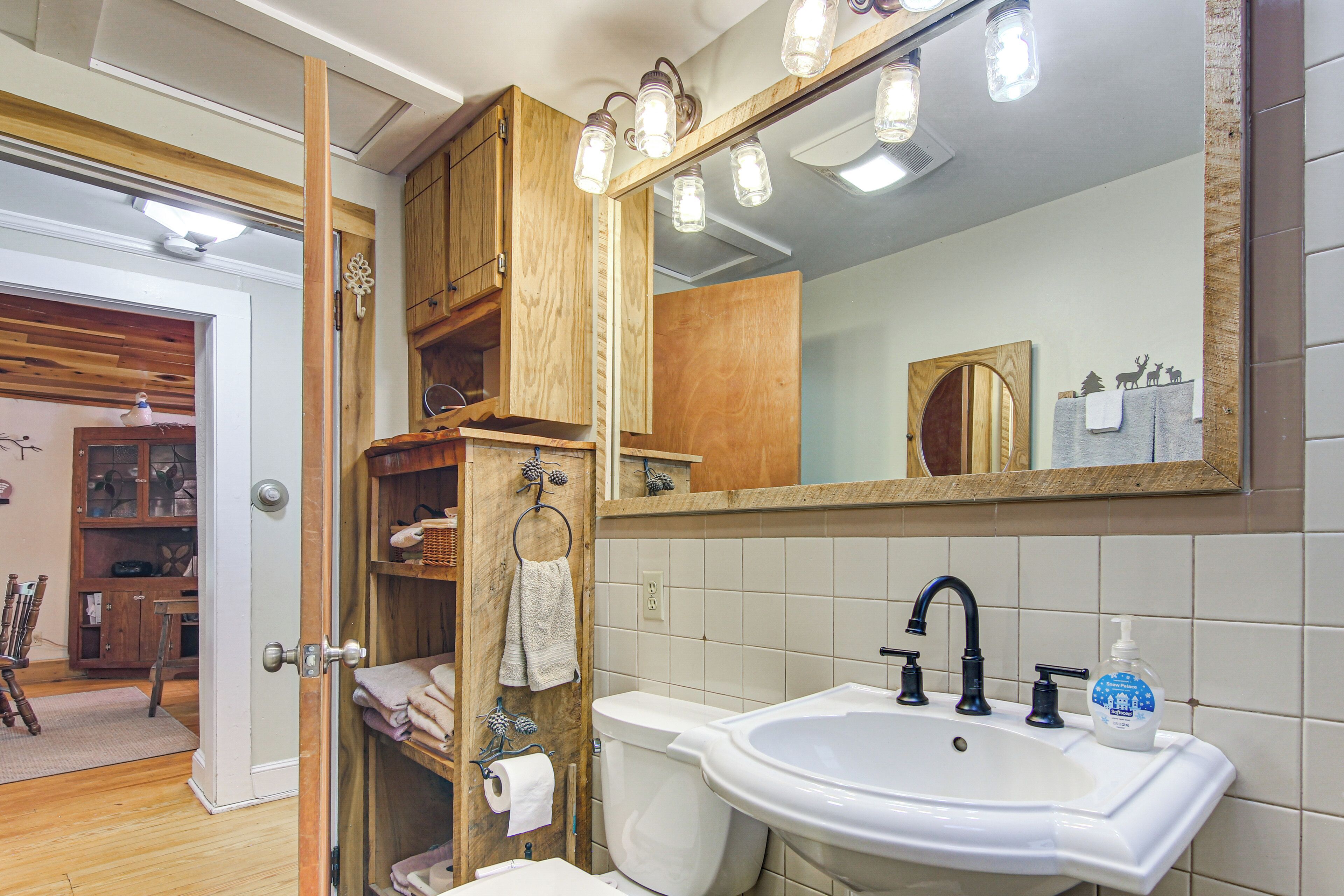 A bathroom with a white sink, a mirror, and wooden shelves.