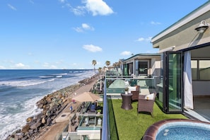 Un balcon donnant sur la mer, avec vue sur l’océan, un jacuzzi et du mobilier d’extérieur.