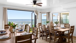 A dining area with a view of the ocean, wooden furniture, and large windows. - Spacious Beachfront Family Retreat - 819-4 (Oceanside)