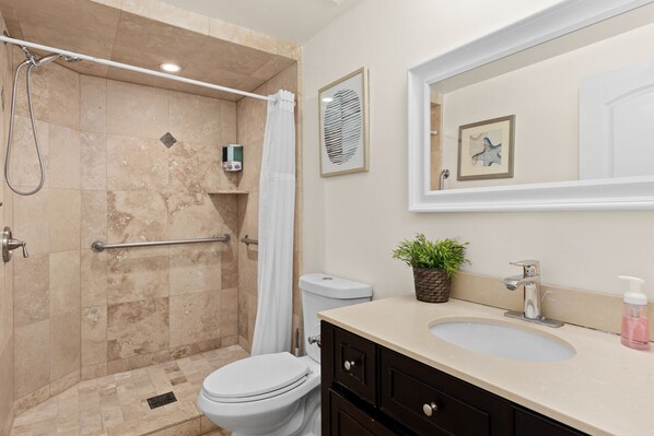 Baño con ducha, inodoro, lavabo y espejo.