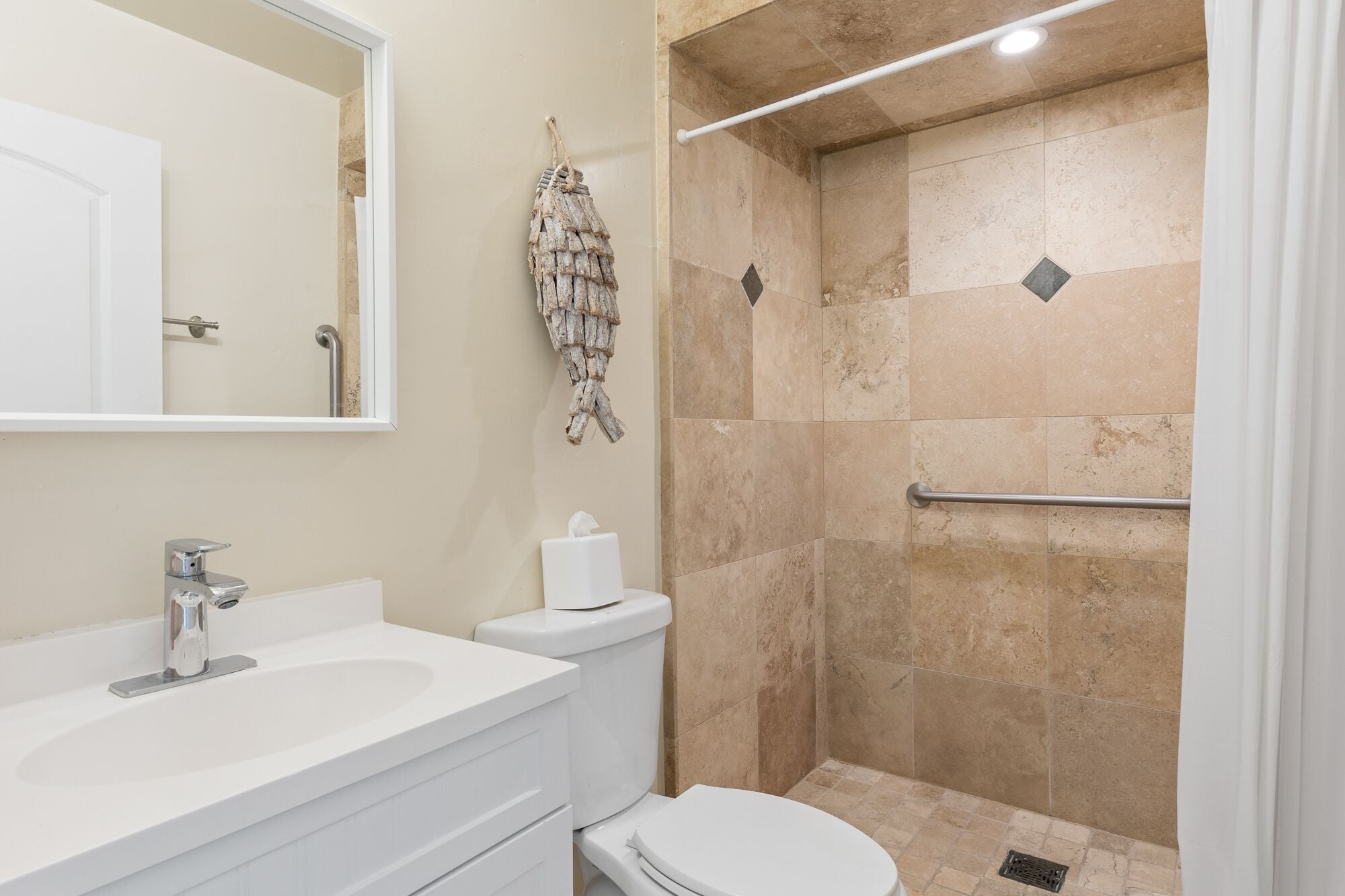 Une salle de bain avec un lavabo, des toilettes et une douche, le tout de couleur blanche.