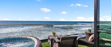 Un balcon doté d’un jacuzzi, de fauteuils en osier et offrant une vue sur l’océan.
