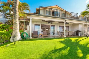 A two-story house with a covered patio, outdoor furniture, and a lawn. - Direct Oceanfront, Sunset Views, Gated Puamana 58-1 (Lahaina)