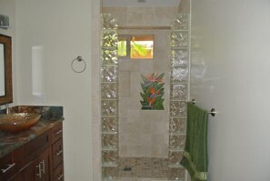A bathroom with a glass shower enclosure, a wooden vanity, and a green towel. - Direct Oceanfront, Sunset Views, Gated Puamana 58-1 (Lahaina)