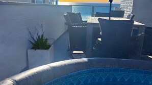 A rooftop pool area with a view of the ocean, a table with chairs, and an umbrella. - Cozy Beachfront Retreat with Private Spa - 1315-1 (Oceanside)