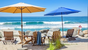 A beach with two wooden chairs and two beach umbrellas, one yellow and one blue, overlooking the ocean. - Cozy Beachfront Retreat with Private Spa - 1315-1 (Oceanside)