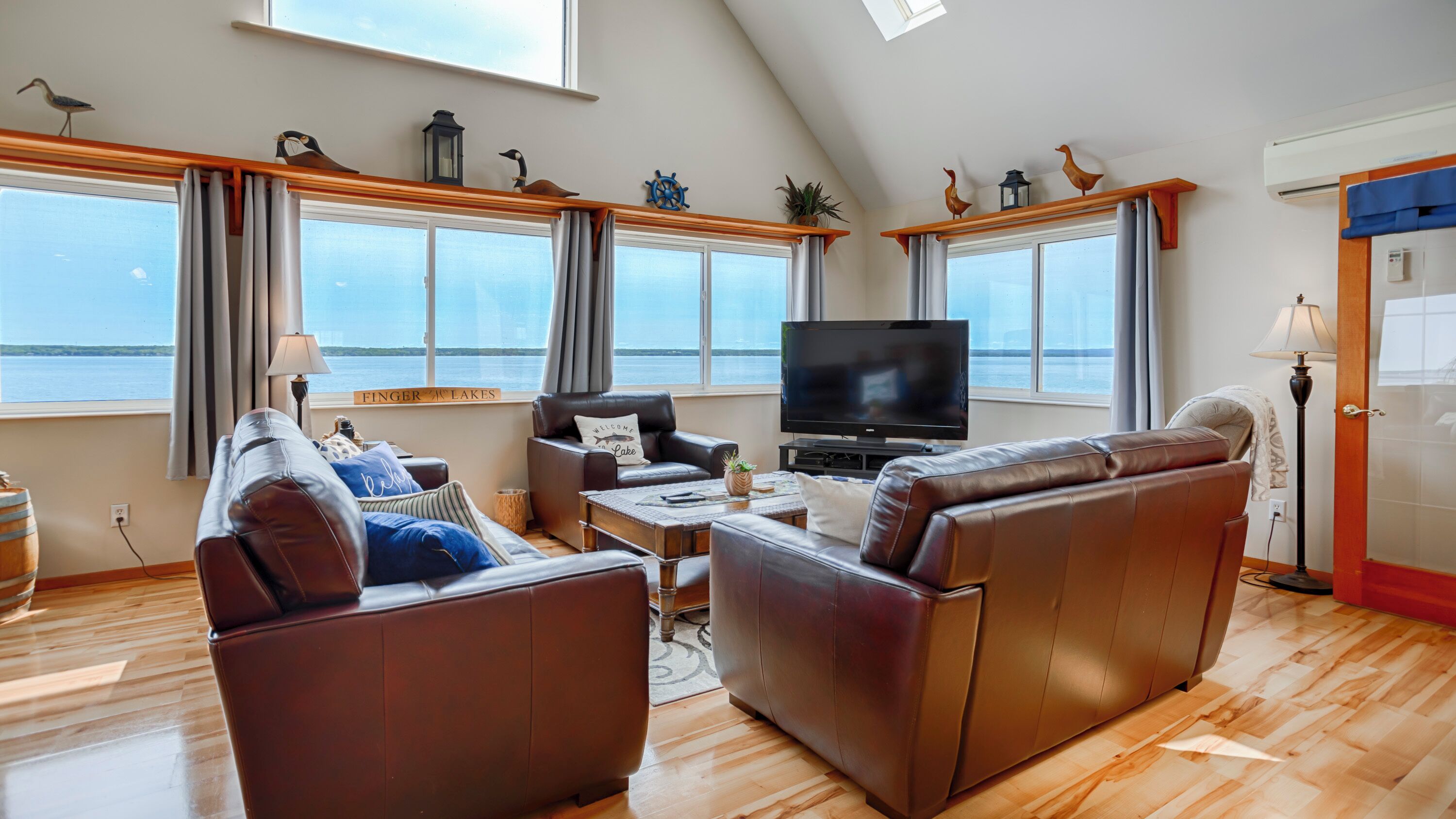 Un salon spacieux avec une grande télévision, des canapés en cuir et une vue sur le lac.
