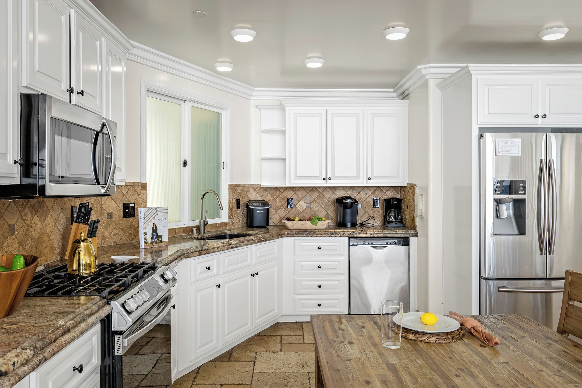 A modern kitchen with white cabinetry, stainless steel appliances, and a granite countertop.