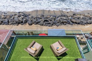 A glass-enclosed pool with two wicker lounge chairs and a red umbrella. - Stunning Waterfront Oasis P823-1 (Oceanside)