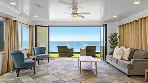 A living room with a view of the ocean, a ceiling fan, and a wooden coffee table. - Stunning Waterfront Oasis P823-1 (Oceanside)