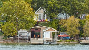 A lakeside property with a dock, a small boat house, and a main house with a visible deck area.