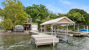 A waterfront property with a dock, a covered pavilion, and a garage.