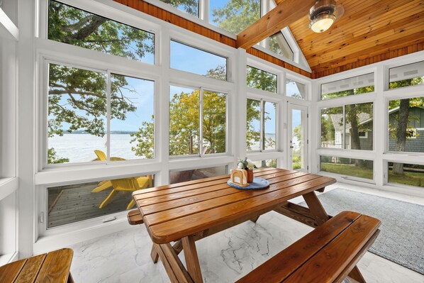 A wooden deck with a table and benches, overlooking a body of water and trees. - Pine Ridge:"A True Gem" (Geneva)