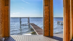 Una terraza de madera con vista a un lago tranquilo y una orilla lejana.