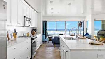 A modern kitchen with white cabinetry, a central island, and a view of the ocean.