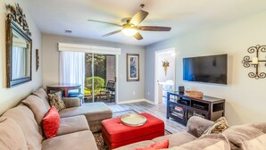 A living room with a ceiling fan, a flat-screen TV, and a fireplace.