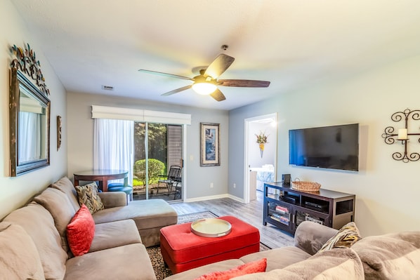 A living room with a ceiling fan, a flat-screen TV, and a fireplace.