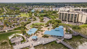 Ein Küstenresort mit Promenadenbau, Zugang zum Strand und einem großen Gebäudekomplex.
