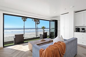 Ein modernes Wohnzimmer mit einem großen Schiebeglasfenster und Blick auf den Strand.