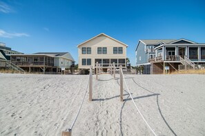 A beachfront property with a large house featuring a balcony and a wooden deck.