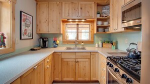 A kitchen with wooden cabinets, a stainless steel sink, and a gas stove. - Charming Estes Park Cabin w/ 2 Private Patios! (Estes Park)