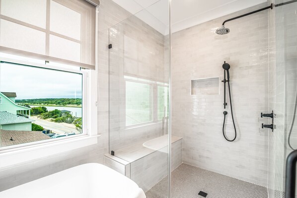 Une salle de bain moderne dotée d’une douche à parois de verre, d’une baignoire et de toilettes.
