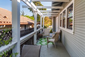 Un balcone coperto con sedie in vimini e un tappeto decorato con motivi verdi.