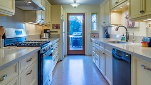 A kitchen with a stove, oven, and dishwasher. There is a window with a view of the outdoors.