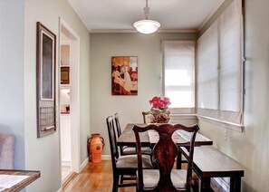 A dining area with a wooden table and chairs, a vase with flowers, and a painting on the wall. - Sleeps 8 + Large Private Deck + Ping Pong | Walk to Downtown | Vin Rouge 51 (Paso Robles)